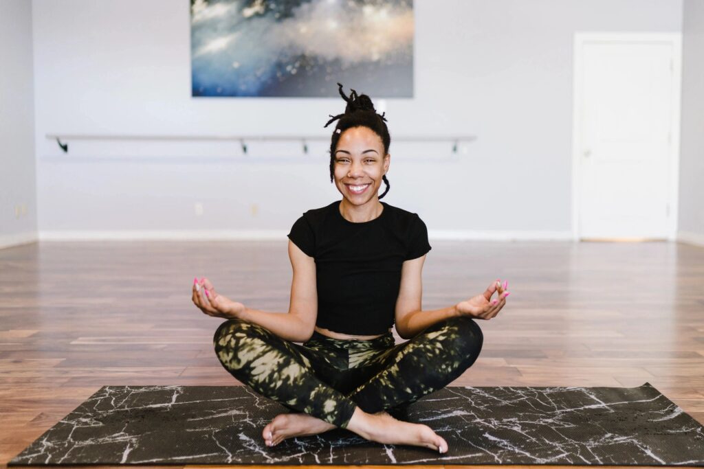 This is a photo of a woman peacefully sitting cross legged on a yoga mat, wearing workout clothes and a smile.  She has her hair in a bun.  Her hands are in a meditative position.  This photo is meant to demonstrate how you can relax while a New Hampshire bankruptcy lawyer like ours is on your side.